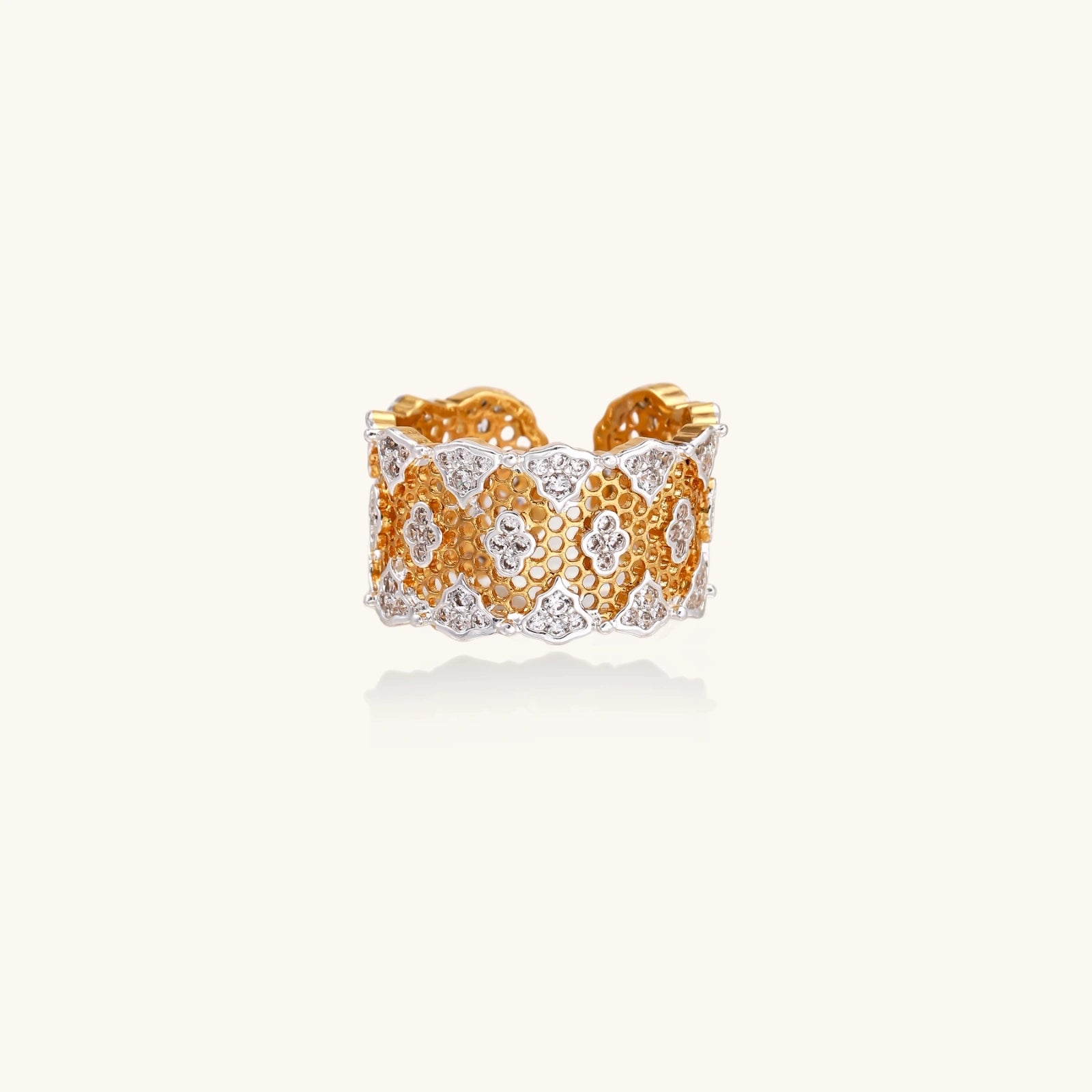 Two-tone gold and silver lattice ring with clover pattern and crystal accents on white background