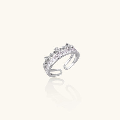 Silver-toned adjustable crown ring with channel-set square zirconia stones and delicate floral details on white background